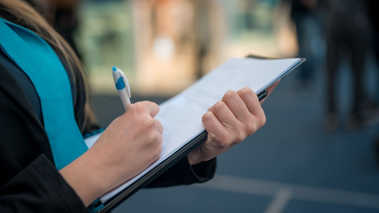 person writing on a clip board